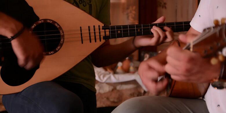 Close-up of two people playing traditional string instruments during an ancient Greek music lab in Crete.