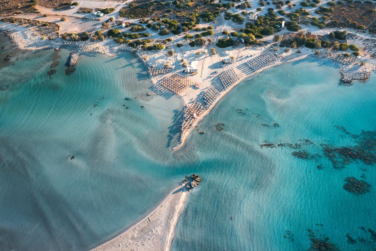 Aerial view of Elafonissi Beach in Crete with turquoise waters and organized sunbeds.