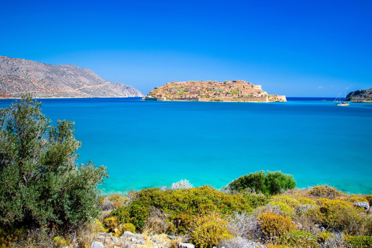 View of Spinalonga Island in Crete surrounded by turquoise sea and rocky hills.