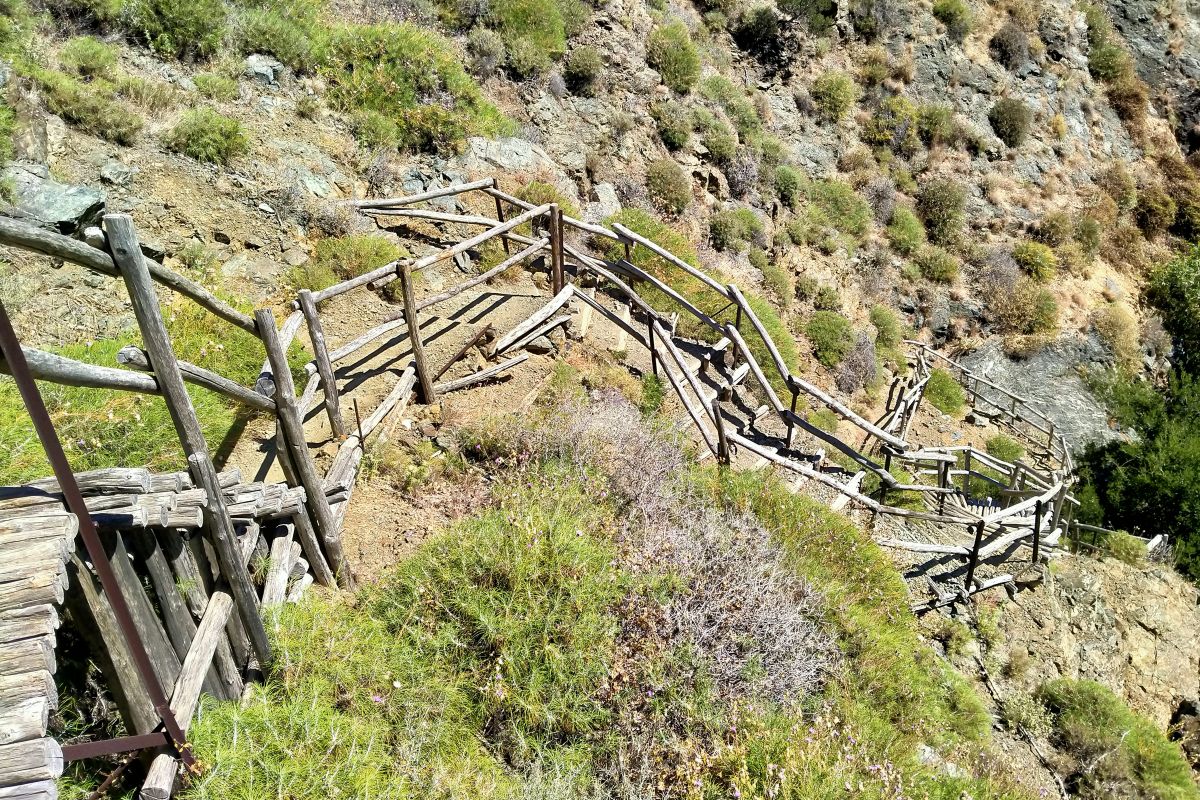 Wooden zigzag path with railings on a steep hillside in Richtis Gorge, a scenic hiking trail among the Crete gorges.