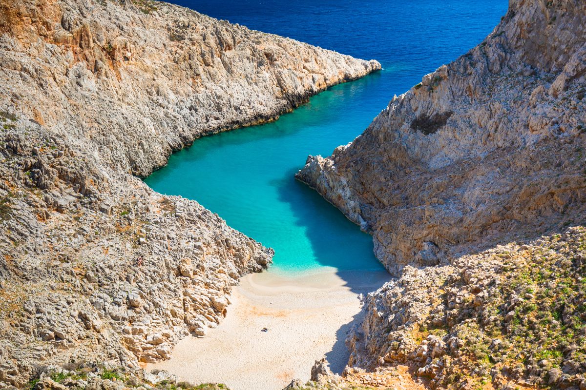 Seitan Limania Beach in Crete Greece with turquoise water, rocky cliffs, and sandy shore.