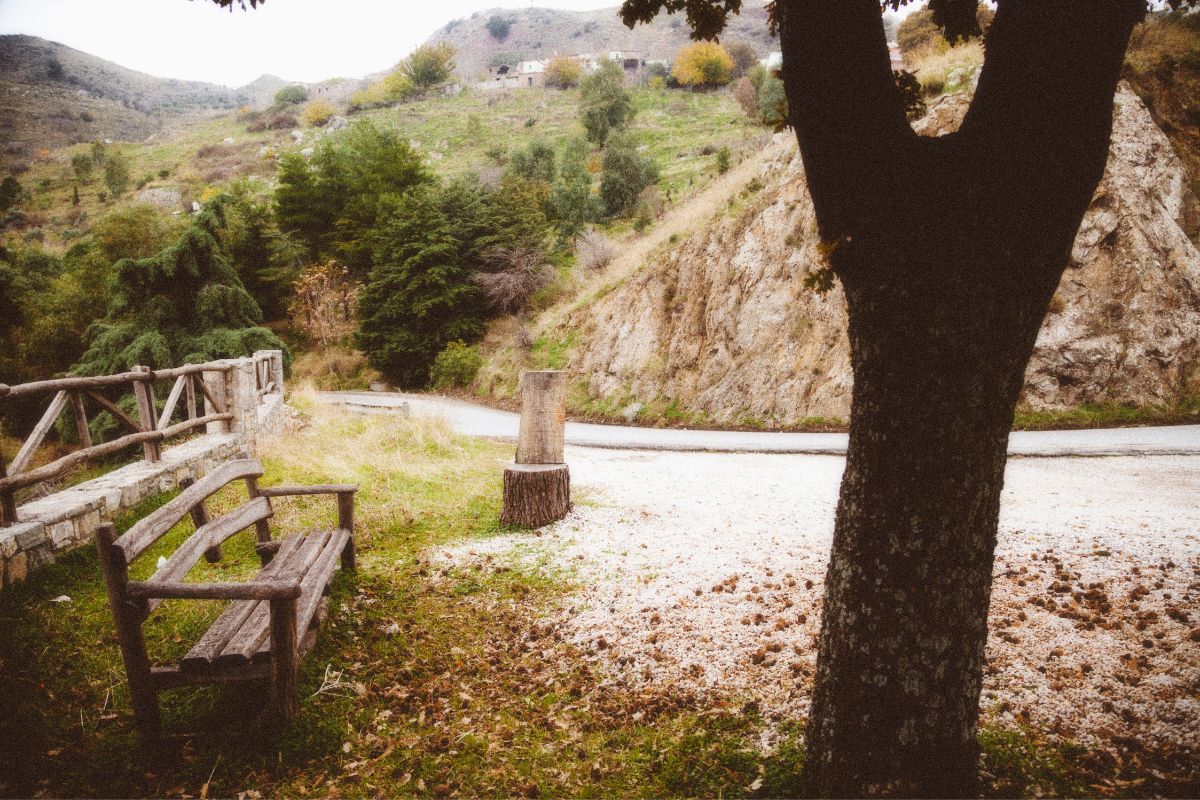 Mountain village scenery near Anogia on Psiloritis, Crete, Greece with a roadside bench.
