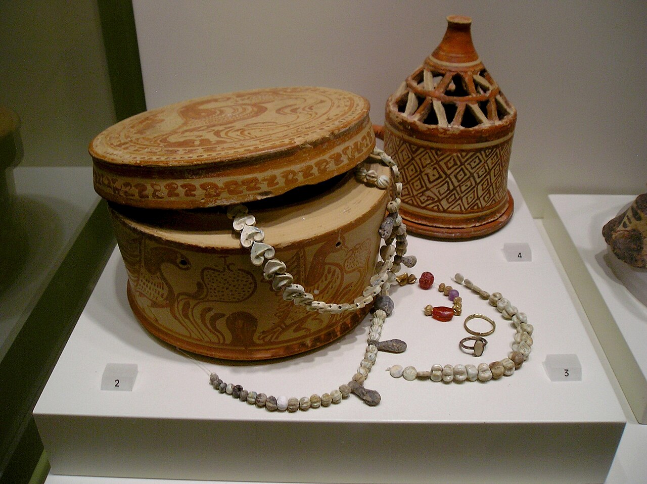 <a href="https://commons.wikimedia.org/wiki/File:Clay_Pyxis_and_jewellery,_Pachyamos,_Crete,_1350-1300_BC,_AMH,_079077.jpg" target="_blank" rel="noopener noreferrer">Clay pyxis and jewellery from Pachyamos, Crete, 1350–1300 BC, Archaeological Museum of Heraklion, photographed by Zde, via Wikimedia Commons (CC BY-SA 4.0).</a>