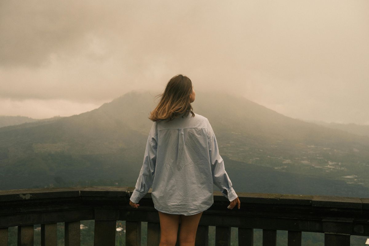 Woman overlooking a misty mountain landscape, reflecting yin and yang balance in nature.