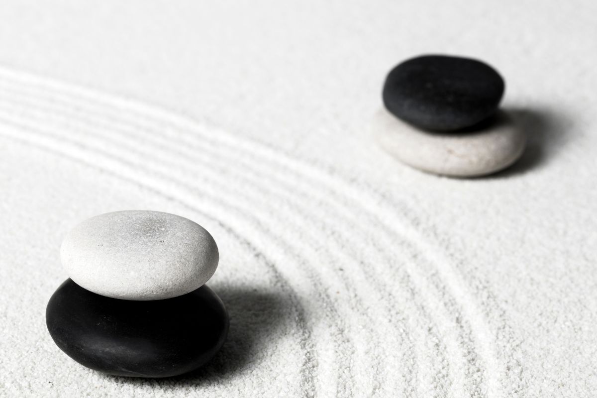 Balanced black and white stones on sand reflecting the yin og yang symbol.
