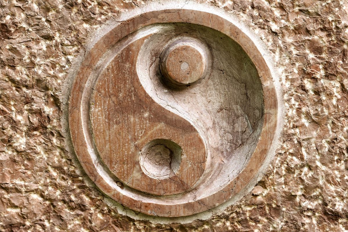 Stone yin og yang symbol carved into a textured wall.