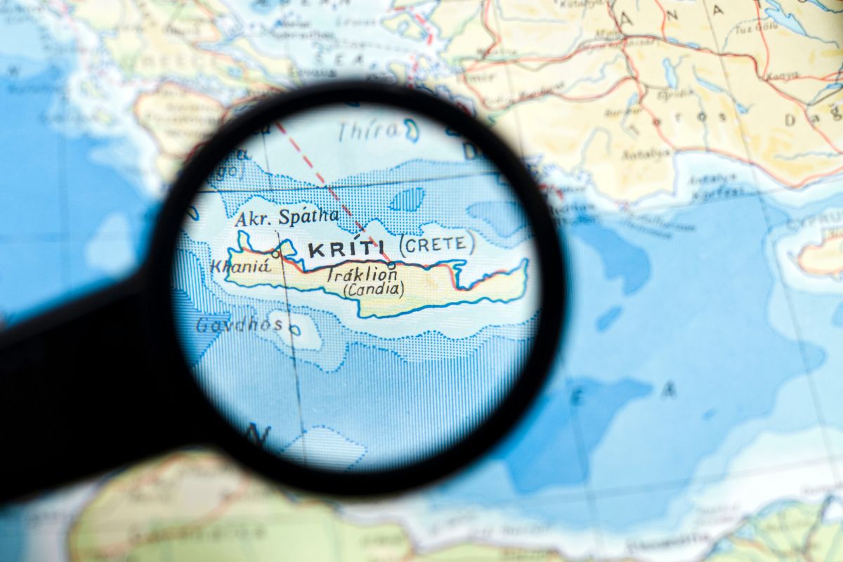 Map of Crete (Kriti), Greece, highlighted under a magnifying glass for an ancient Crete history guide.