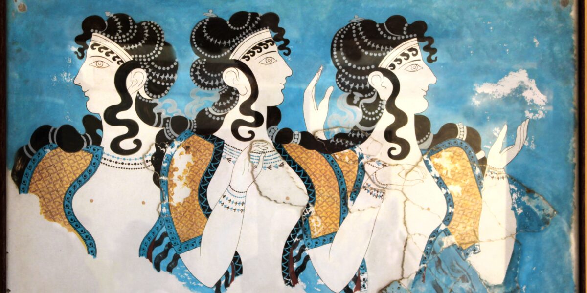 A heavily restored Minoan fresco titled Ladies in Blue from the Palace of Knossos, Crete, depicting three ancient Minoan women with elaborate hairstyles, jewelry, and traditional open-front dresses against a vibrant blue background.