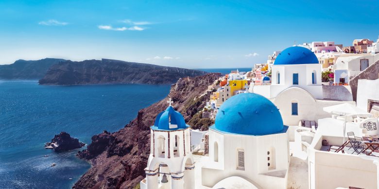 Coastal village with iconic blue-domed buildings overlooking the sea.