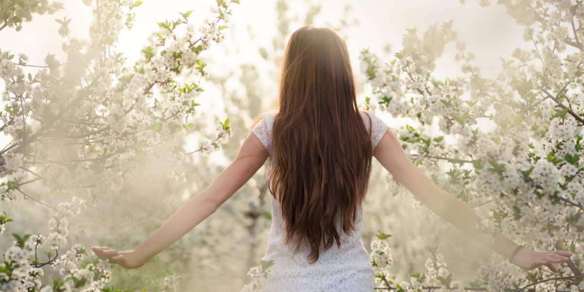 Woman in a blooming garden at sunrise, symbolizing renewal, intuition, and Divine Feminine awakening energy.