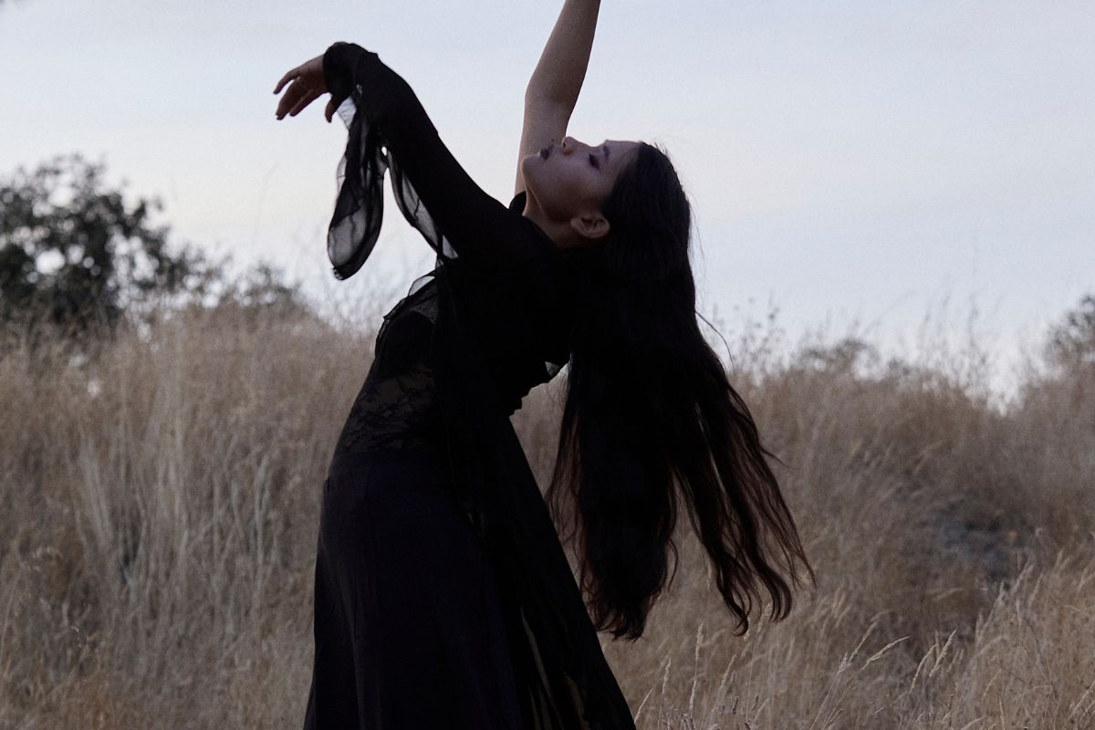 Woman practicing gentle movement meditation outdoors, symbolizing embodiment and Divine Feminine awakening energy.