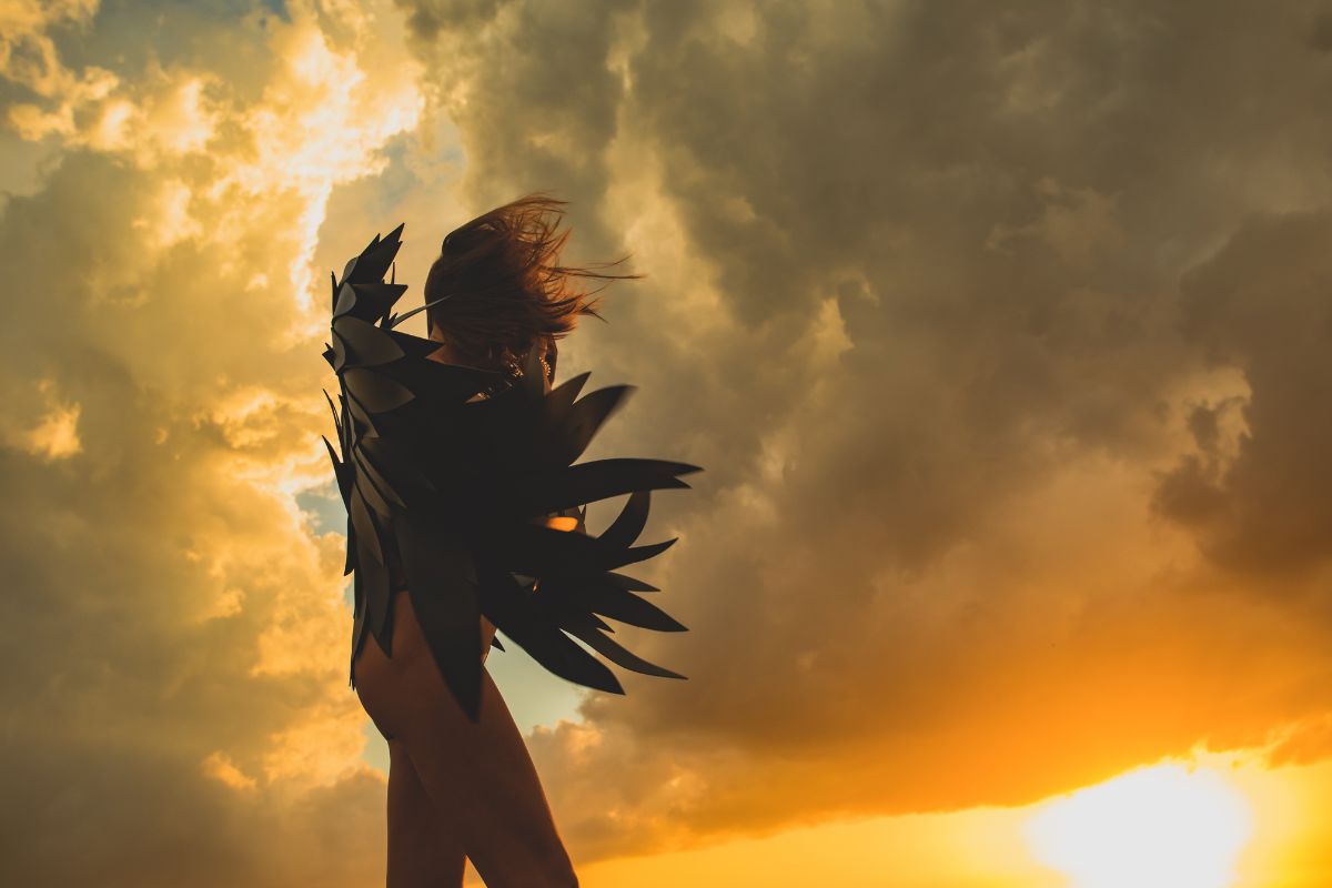 Silhouette of a woman in dramatic sunset light, representing inner silence and transformation in a Divine Feminine awakening.