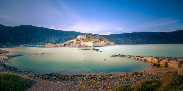 View of Spinalonga island with its historic fortress surrounded by calm waters in Crete during December.