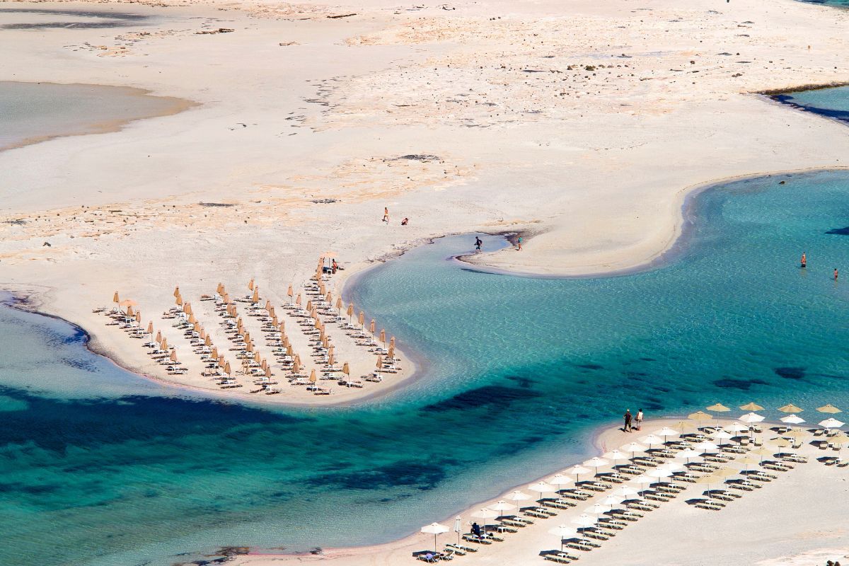 Balos Beach aerial view with turquoise water and many beach umbrellas.
