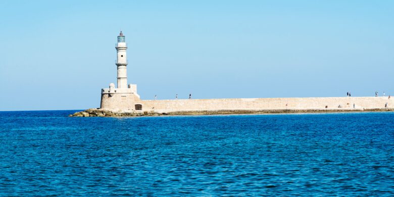 Chania Lighthouse in Crete with clear blue skies and calm sea during September.