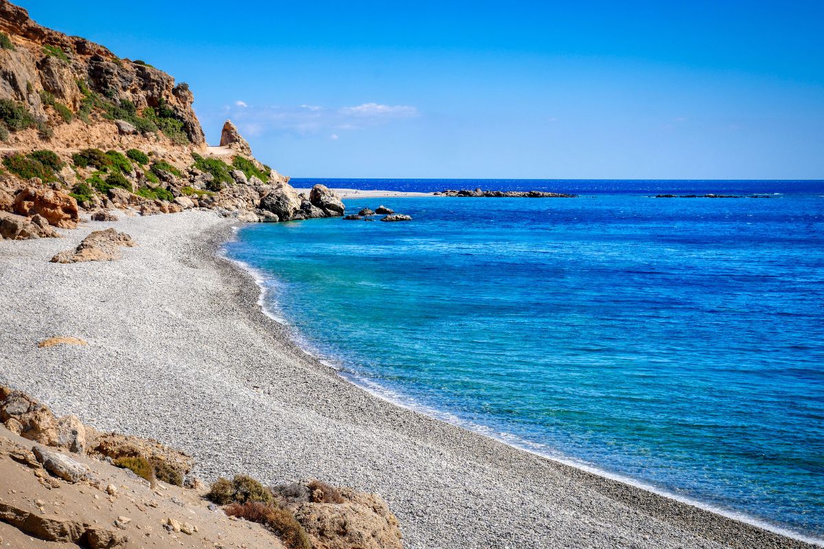 Pebble beach with clear blue waters in Crete during September, ideal for swimming and relaxing.