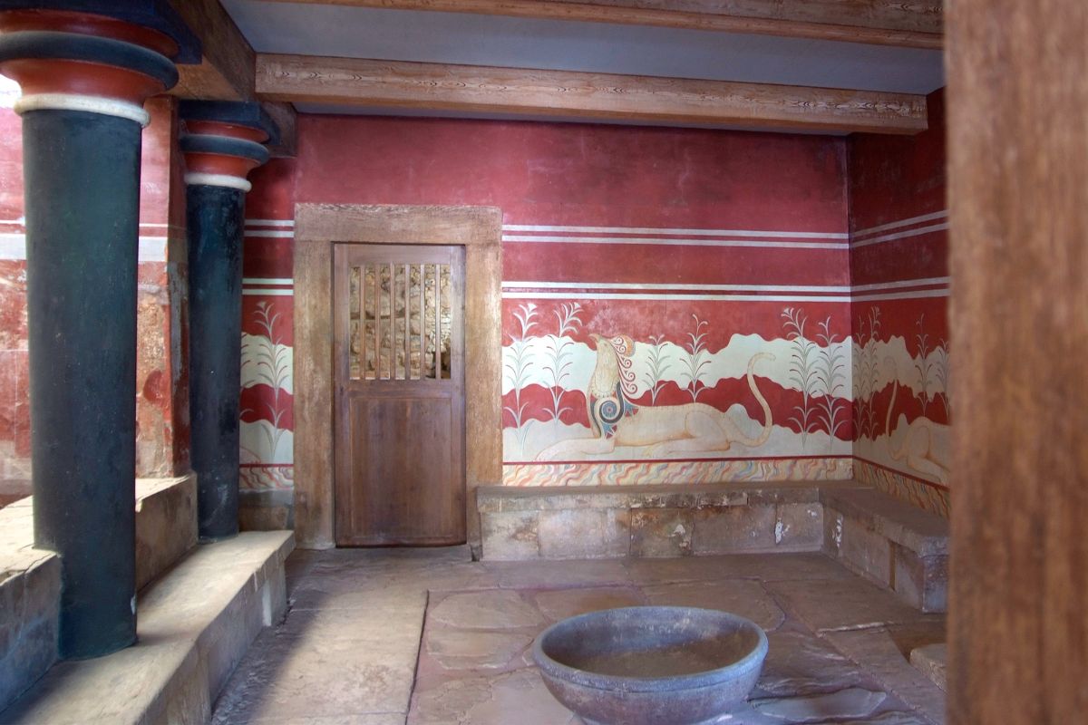 Interior view of the Throne Room at Knossos Palace in Crete, featuring Minoan frescoes and red columns, an iconic archaeological site in Heraklion Greece.