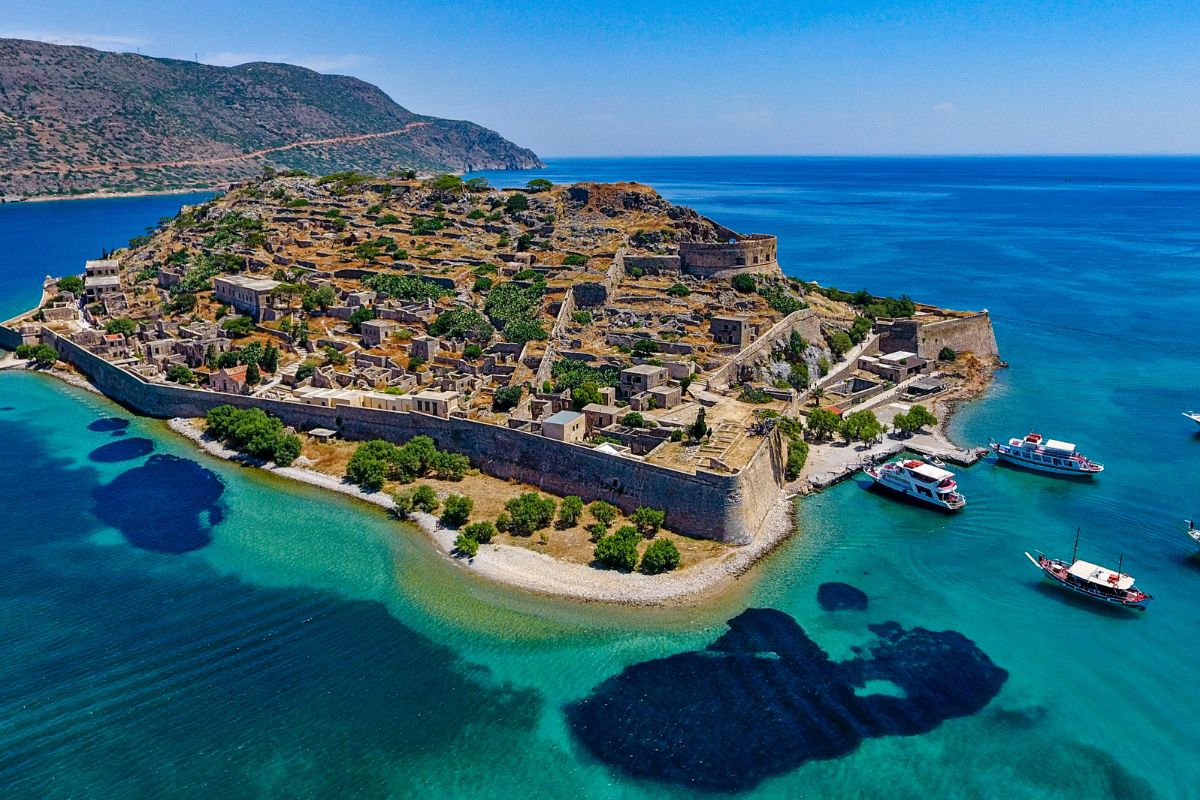 Aerial view of Spinalonga Island in Crete, Greece, showing historic fortifications surrounded by turquoise sea.
