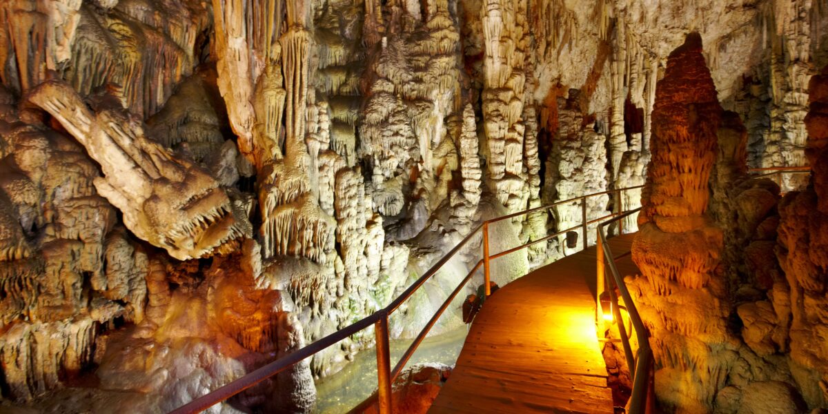 Interior of Dikteon Cave, an iconic Zeus Crete site, with a lit walkway among rock formations.