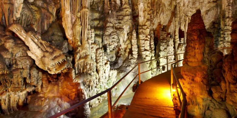 Interior of Dikteon Cave, an iconic Zeus Crete site, with a lit walkway among rock formations.