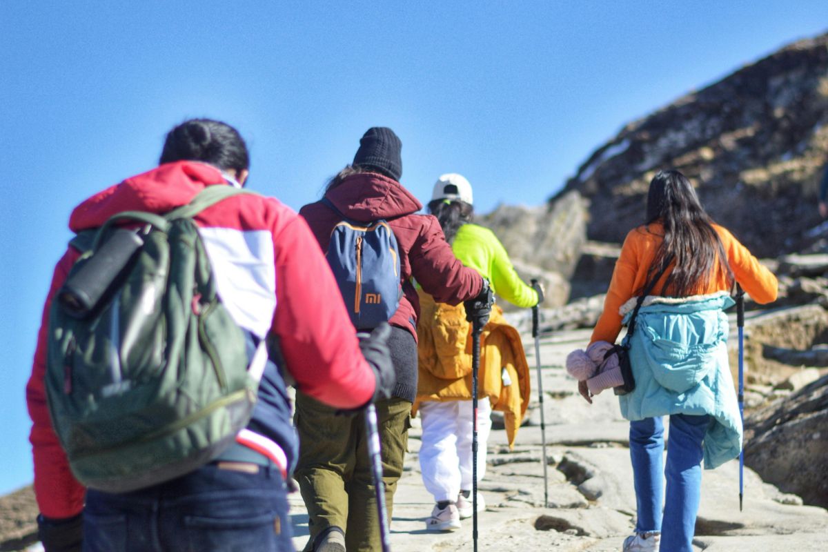 Group of hikers in colorful jackets and backpacks walking uphill with trekking poles, illustrating recommended gear for the Imbros Gorge hike.