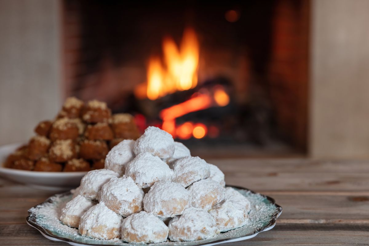 Kourabiedes and melomakarona Greek Christmas cookies by a fireplace, traditional treats for Christmas in Crete.