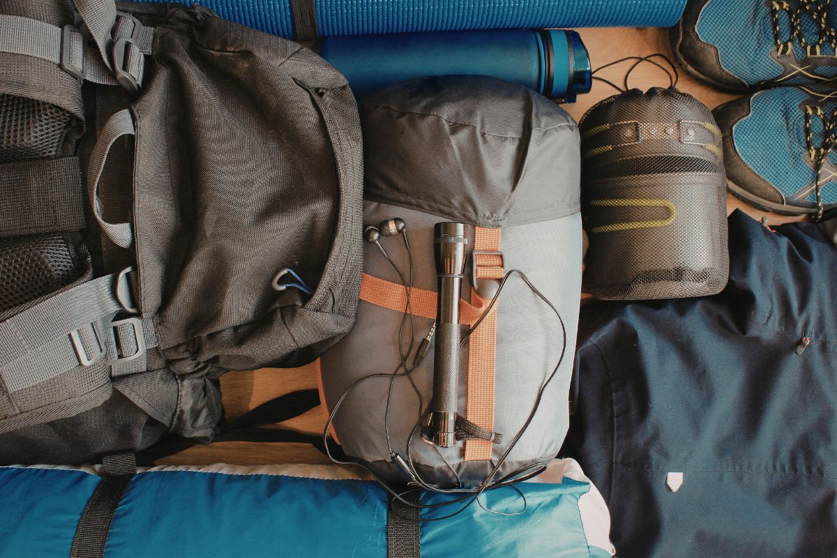 Hiking backpack and essential gear laid out for a Psiloritis Crete hike, including boots, sleeping bag, and water bottle.