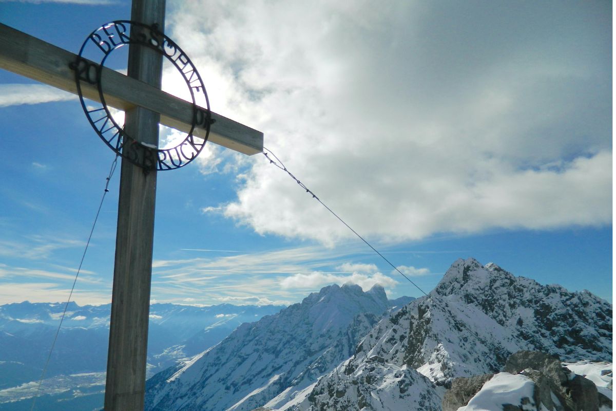 Summit cross at Timios Stavros on Mount Ida Crete (Psiloritis) with snowy mountain peaks and clouds.