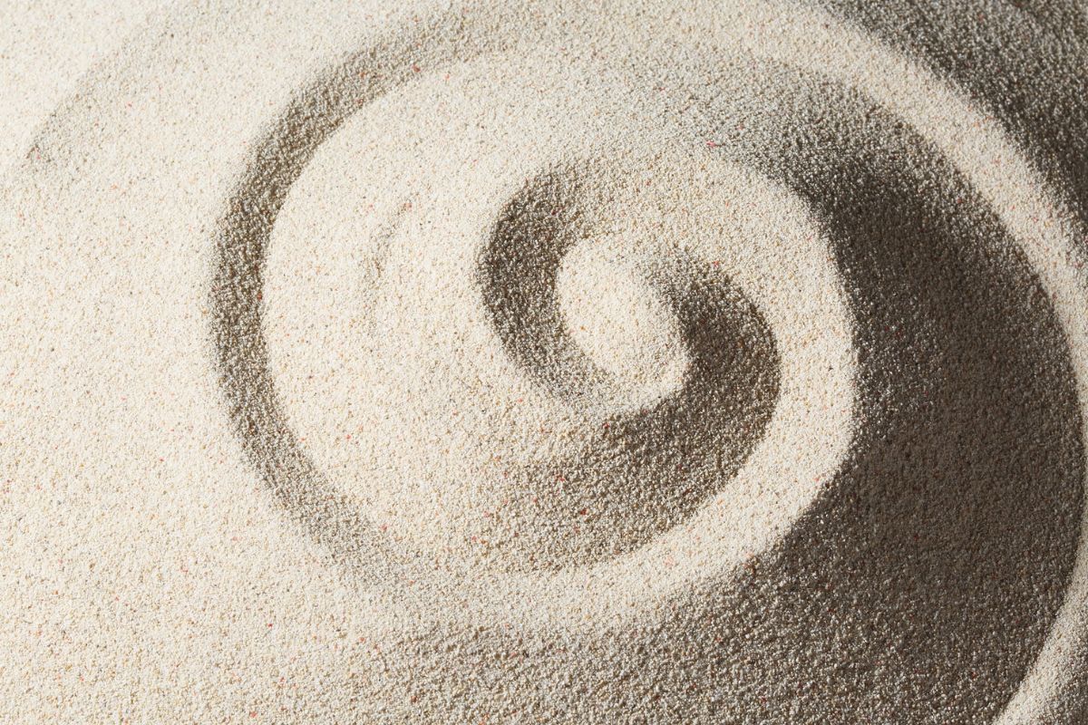 Spiral symbol drawn in sand, representing Divine Feminine Goddess cycles, intuition, and transformation.