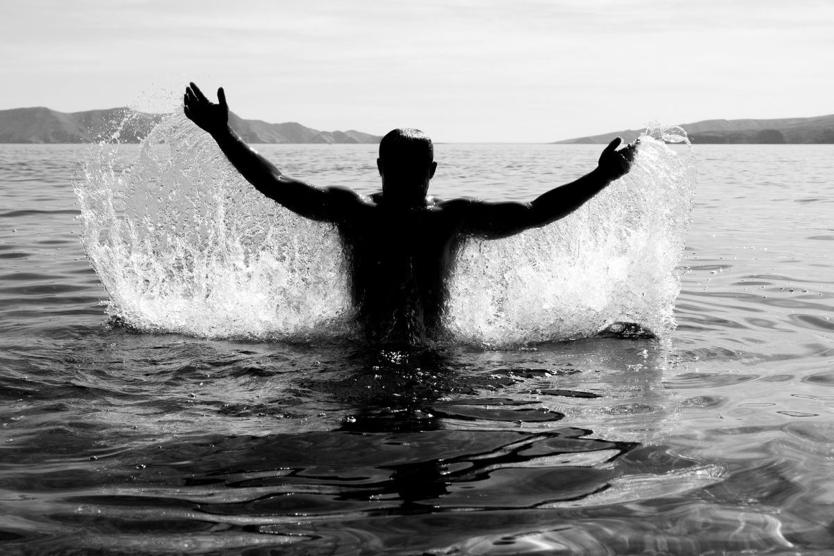 Black-and-white image of a man rising from the sea, symbolizing divine masculine energy, strength, and emotional release.