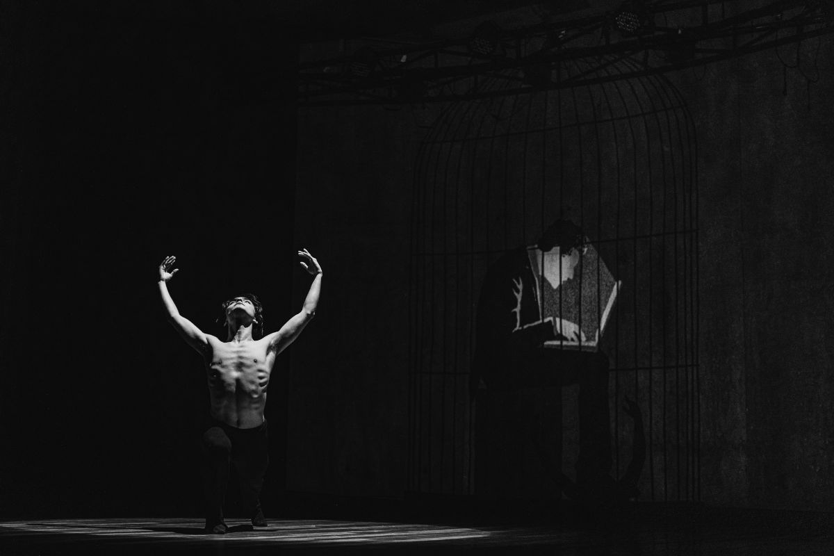 Man on a dark stage in a powerful pose, representing divine masculine energy, strength, and inner transformation.