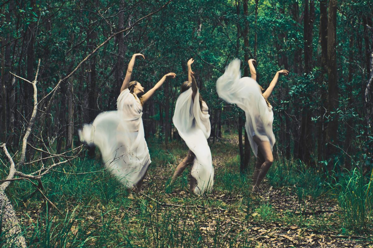 Women dancing in a forest, symbolizing healing the feminine energy through movement, nature, and embodied release.