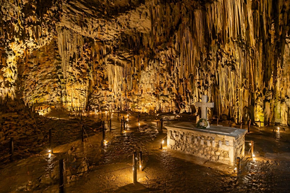 Melidoni Cave in Crete with illuminated stalactites, a stone memorial, and underground walking paths.