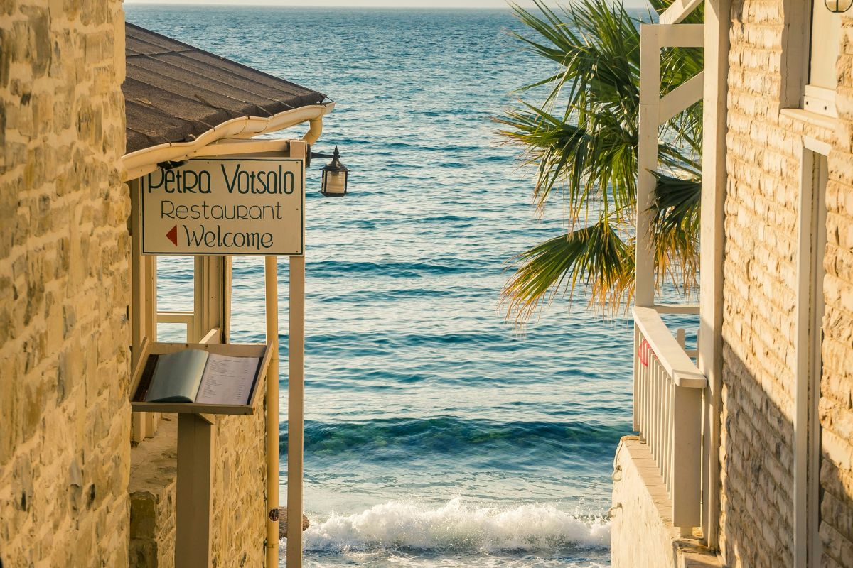 Seaside taverna in Matala, Crete with stone buildings, palm trees, and views of the Libyan Sea