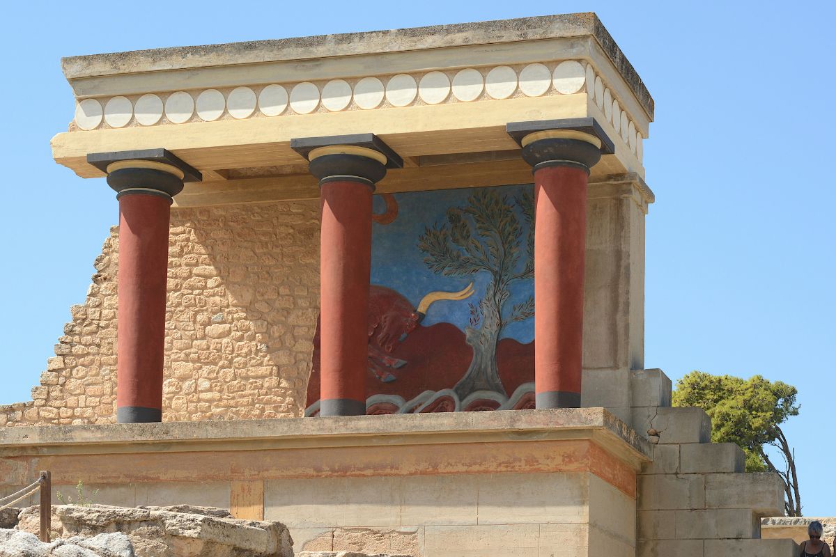 Restored Minoan columns and fresco at Knossos Palace in Crete under a clear blue sky
