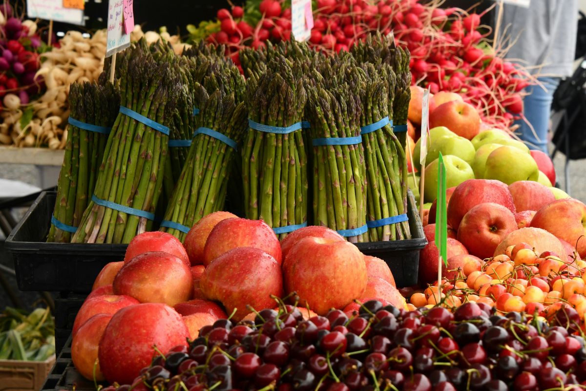 Fresh spring produce at a Cretan market with asparagus, apples, cherries, and seasonal vegetables