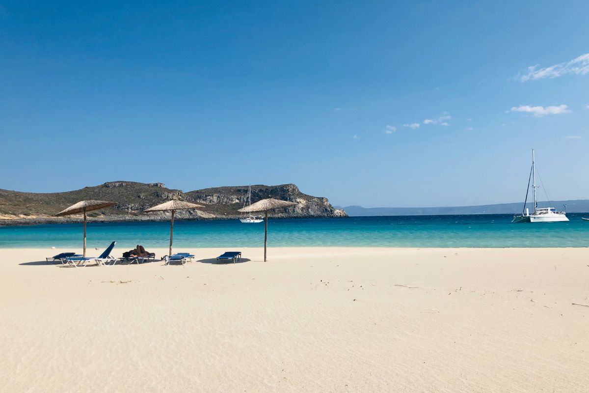 Elafonissos Beach in Crete with white sand, turquoise water, and sun umbrellas in June.