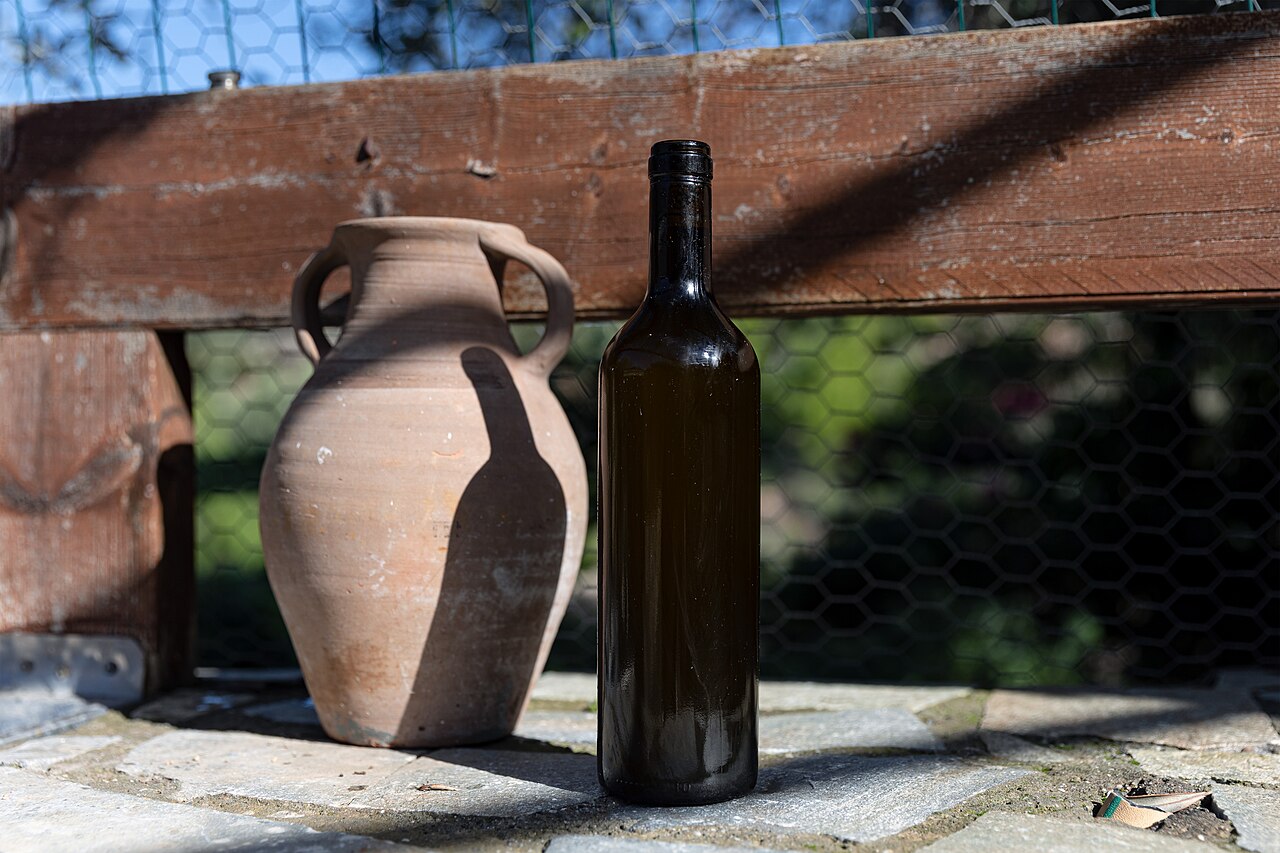 Bottle of fresh olive oil beside a ceramic amphora in Archangelos, Rhodes
