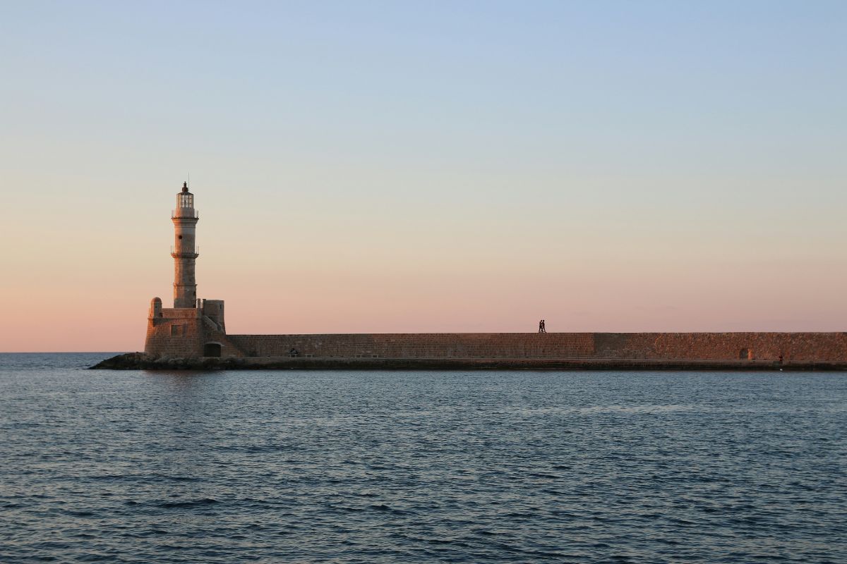 Chania Old Port in Crete with the Venetian lighthouse and calm sea at sunset.